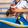Female flag football player holding a football running